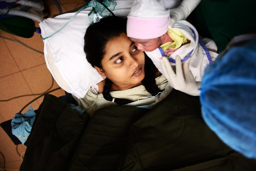 A mother receives the first touch of her newborn in Dhaka, Bangladesh.